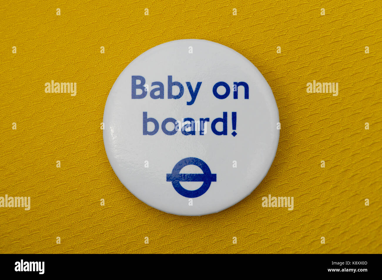 A London Underground Baby on Board badge worn on a yellow fabric
