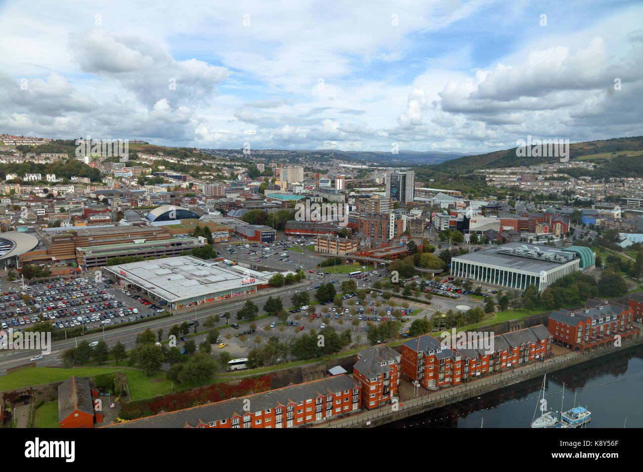 Looking out across Swansea city over the rooftops towards the valleys with supermarket car park and a liesure centre  and waterside apartments Stock Photo