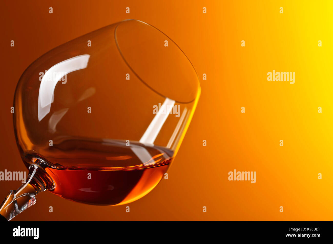 Snifter of brandy with copy space for text on a yellow background Stock
