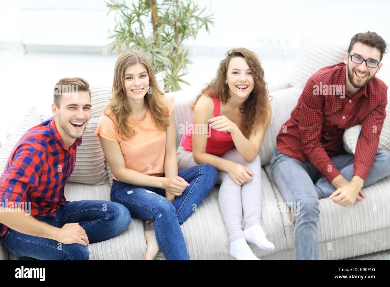 group of cheerful friends watching videos, sitting on the couch in the ...