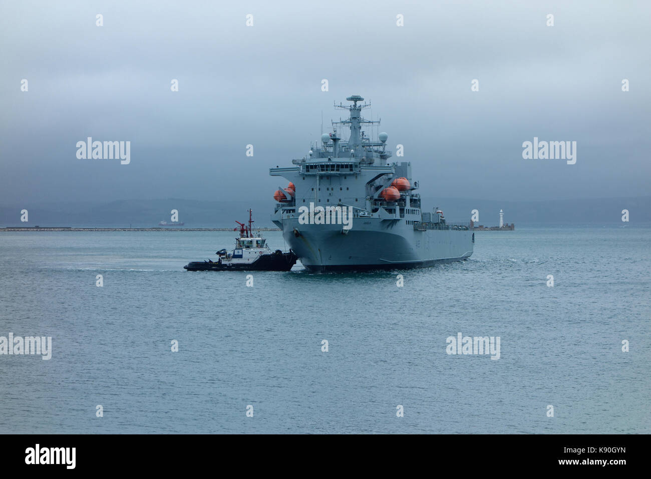 A tug assists RFA Argus vessel to berth in Portland Harbour. Stock Photo