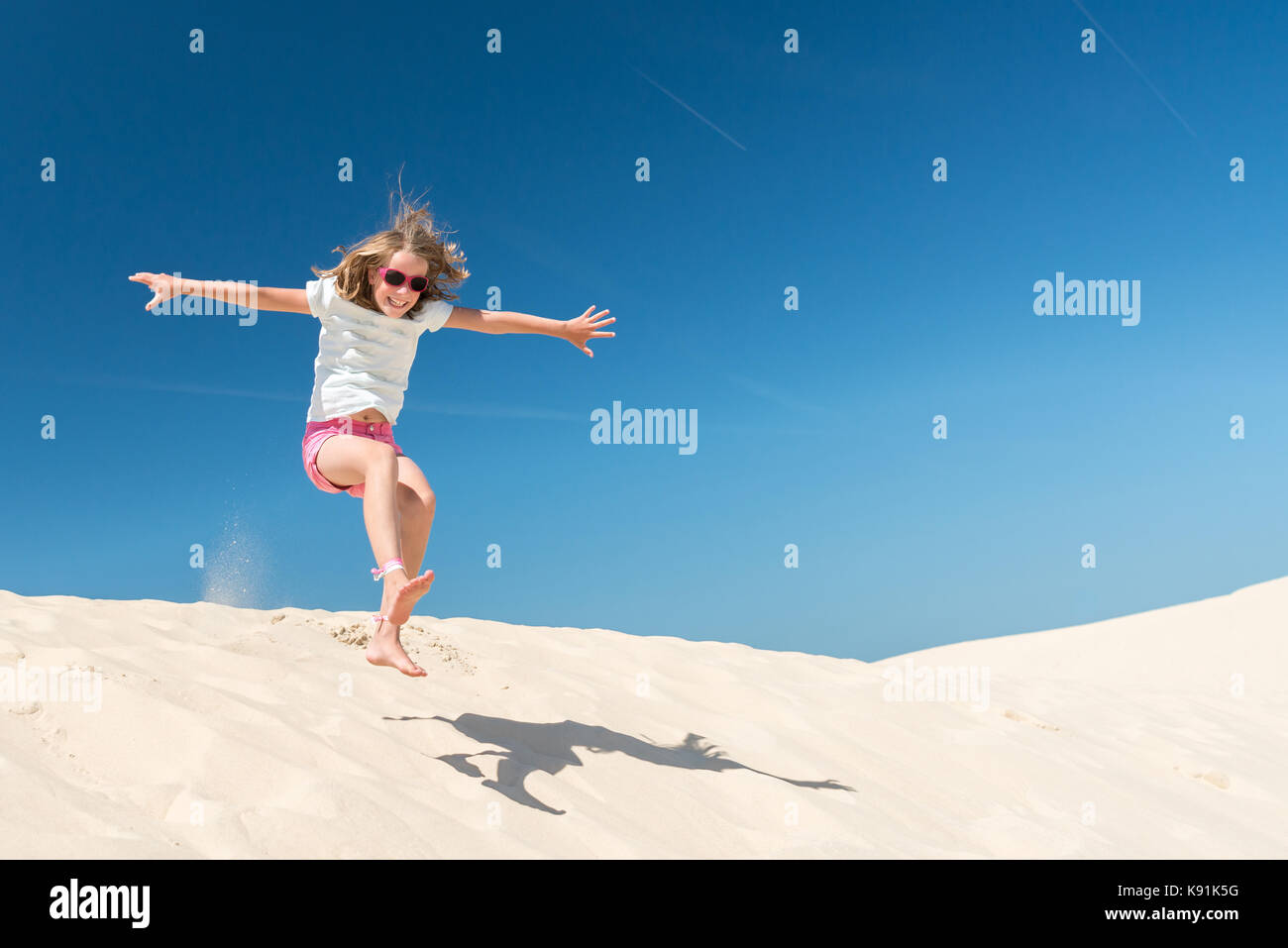 Jumping young girl in front of blue sky Stock Photo - Alamy