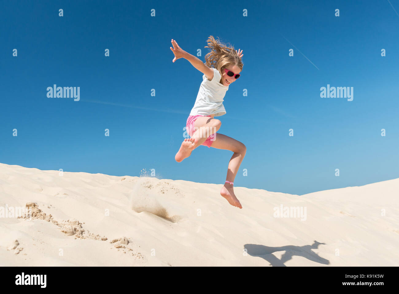 Jumping young girl in front of blue sky Stock Photo - Alamy
