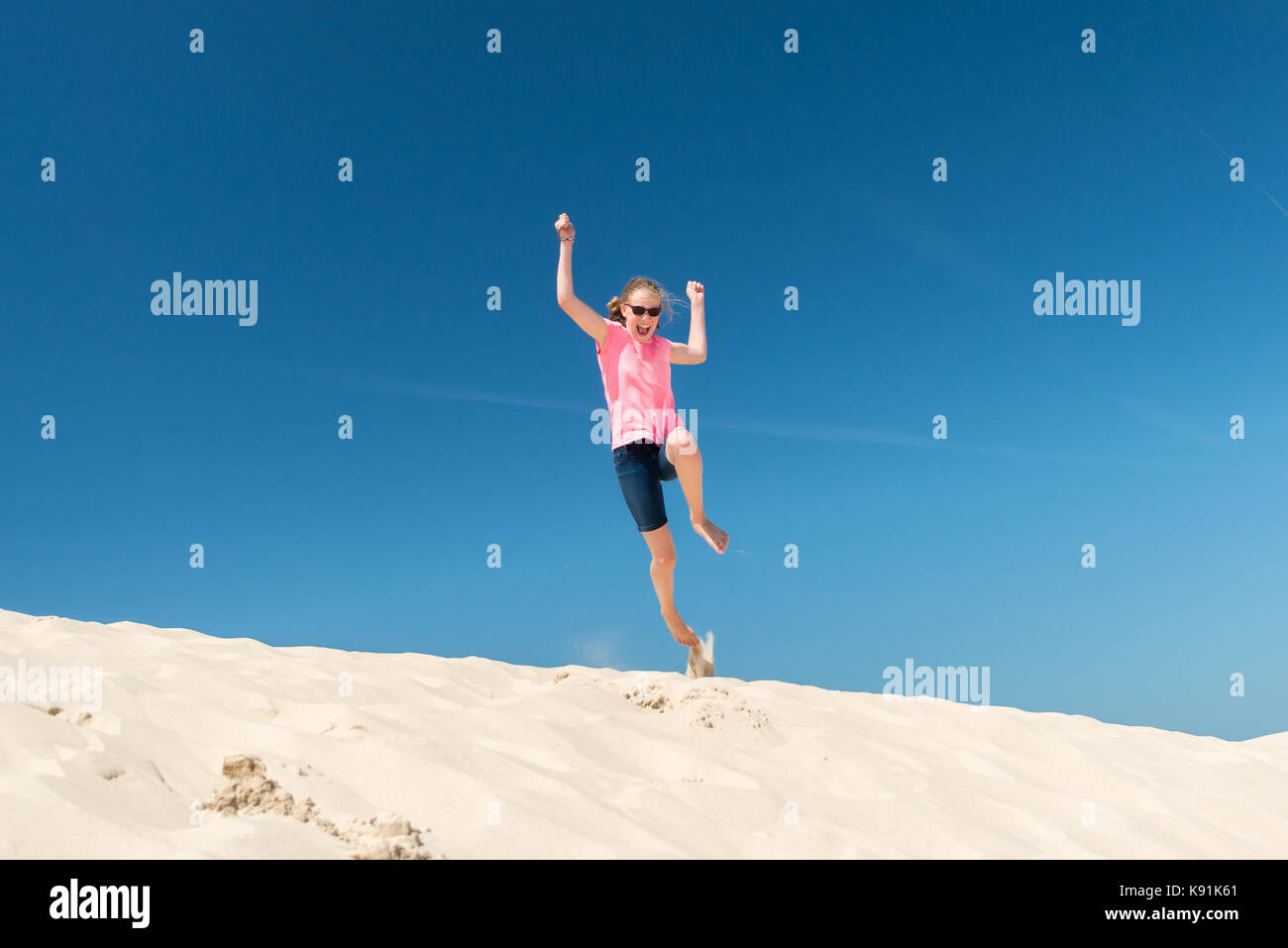 Jumping young girl in front of blue sky Stock Photo - Alamy