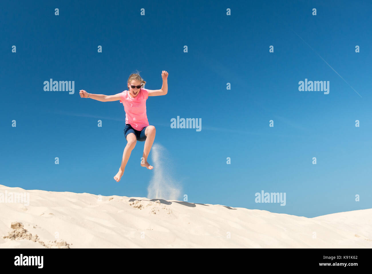 Jumping young girl in front of blue sky Stock Photo - Alamy