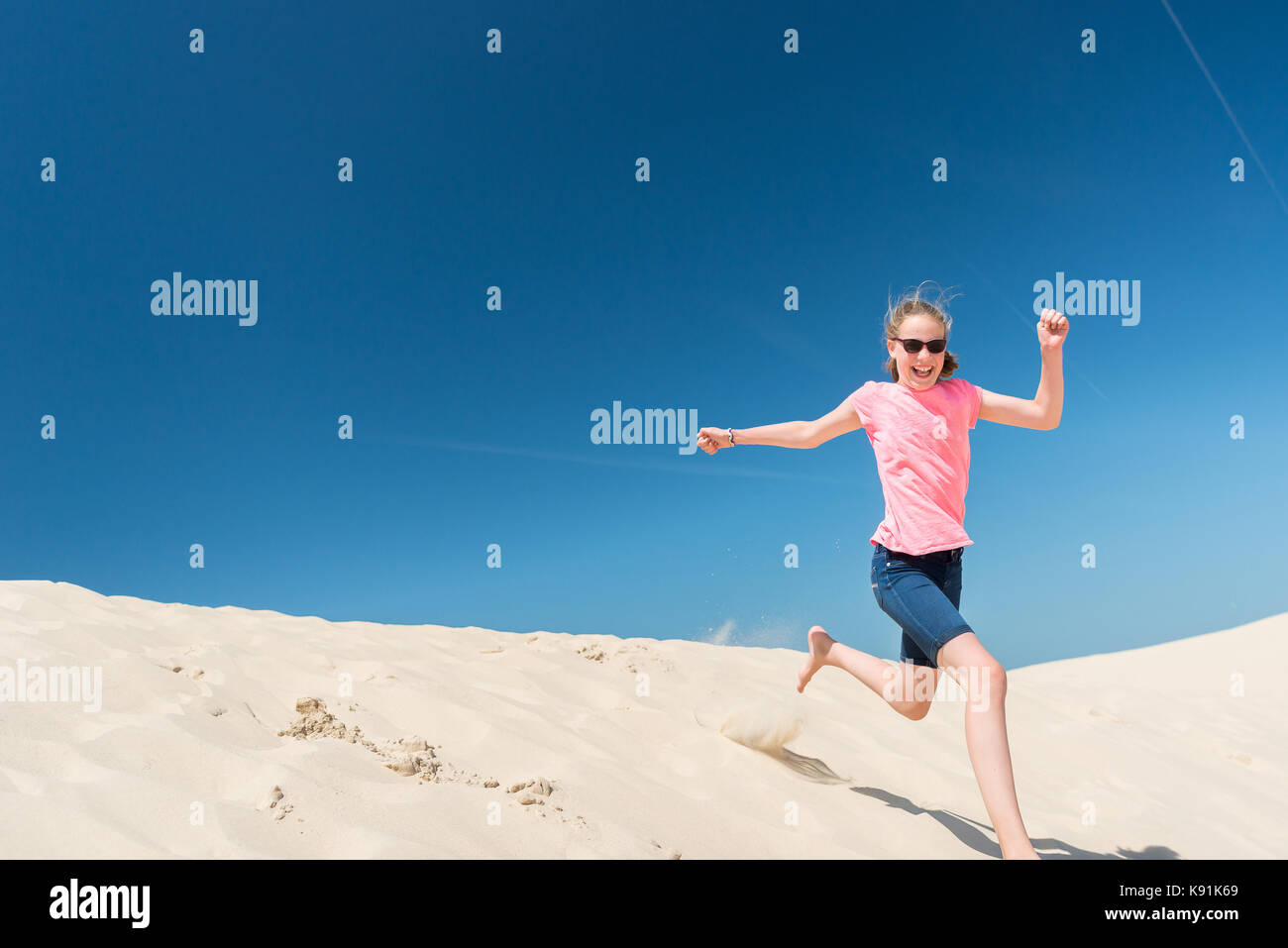 Jumping young girl in front of blue sky Stock Photo - Alamy