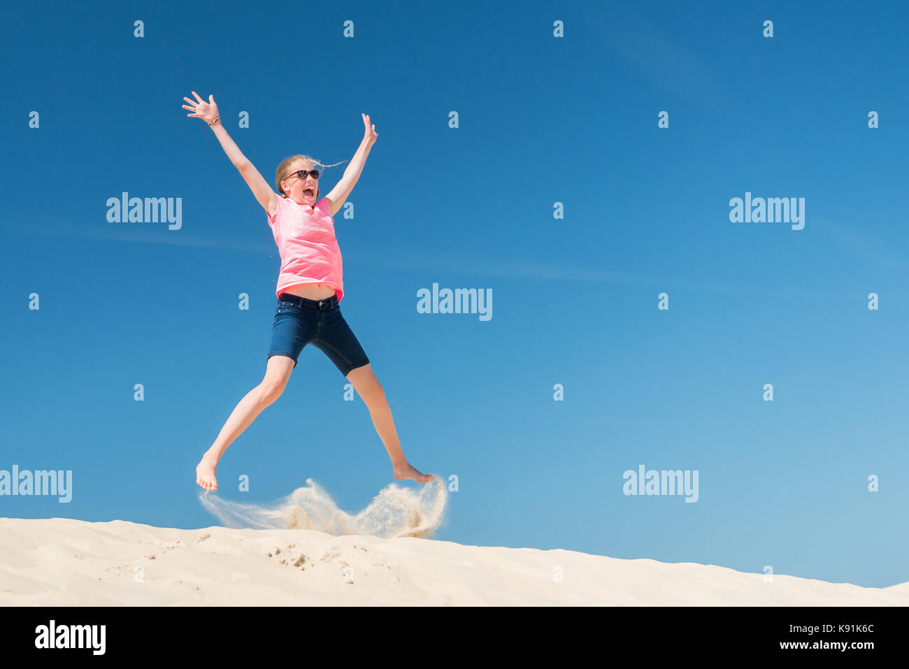 Jumping young girl in front of blue sky Stock Photo - Alamy