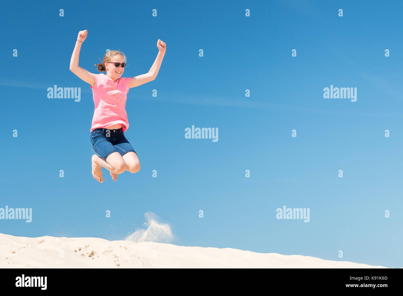 Jumping young girl in front of blue sky Stock Photo - Alamy