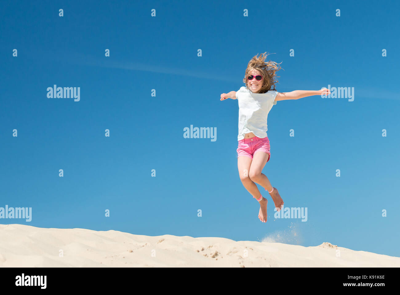 Jumping young girl in front of blue sky Stock Photo - Alamy