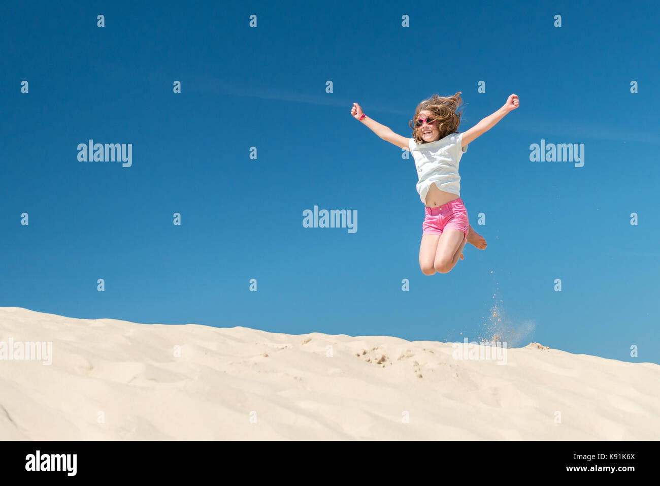 Jumping young girl in front of blue sky Stock Photo - Alamy