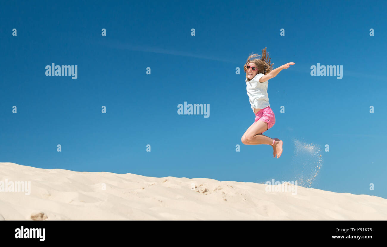 Jumping young girl in front of blue sky Stock Photo - Alamy