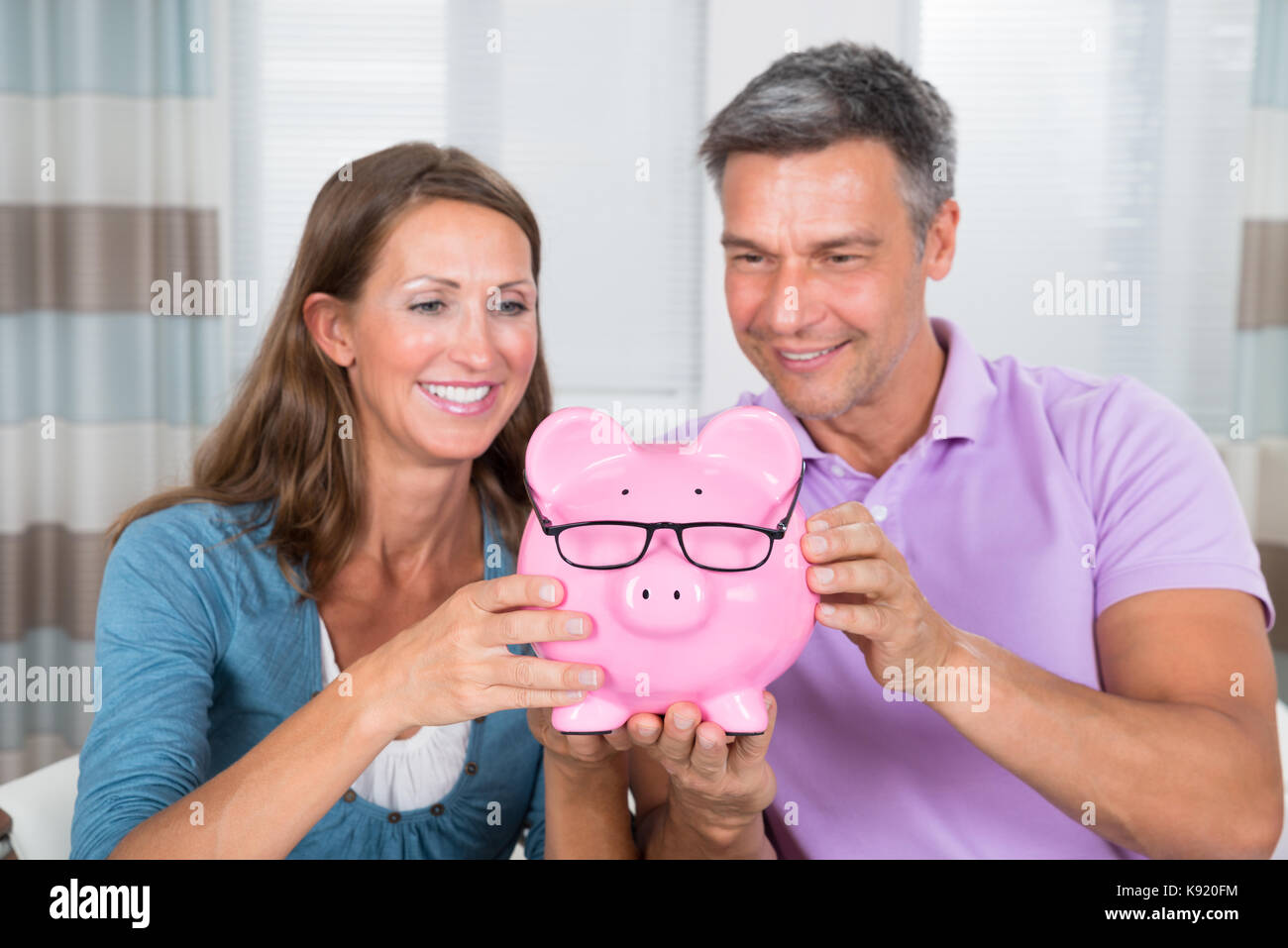 Portrait Of A Smiling Couple Holding Piggybank Stock Photo - Alamy