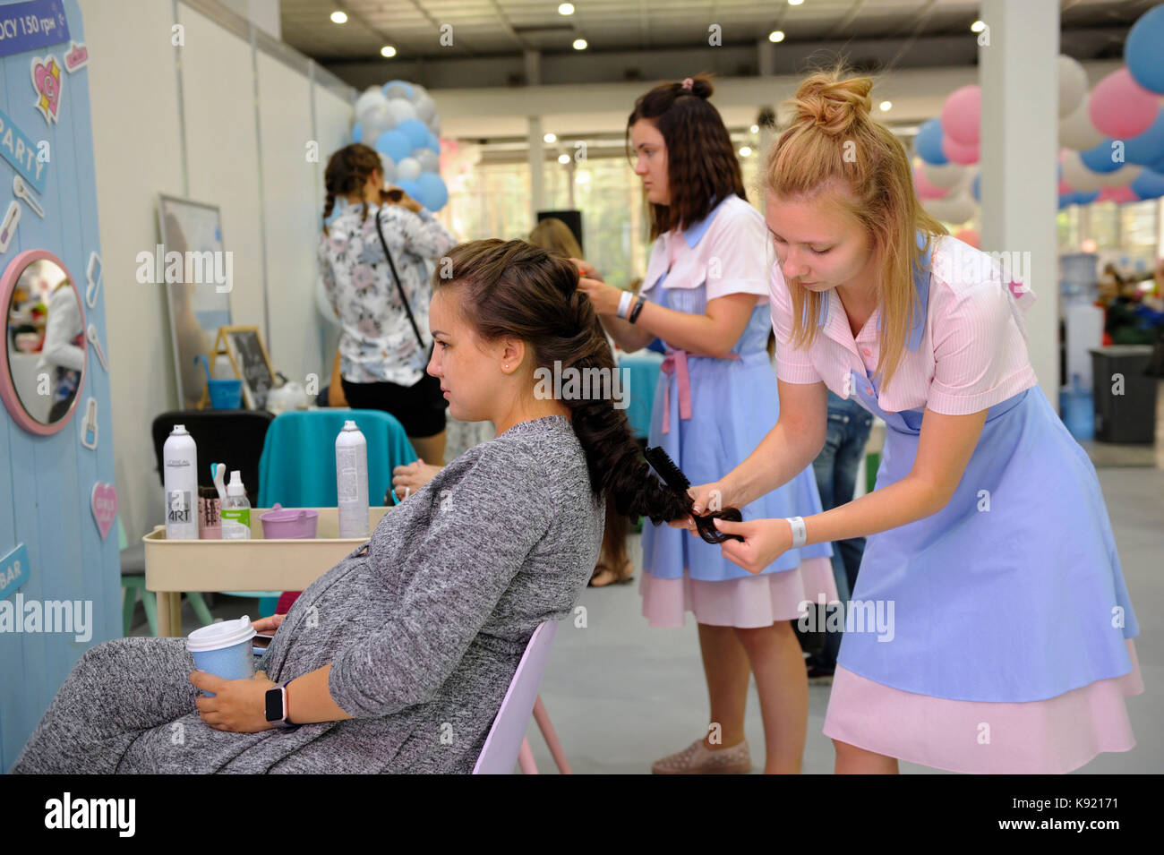 Two hairdressers making hair of pregnant women done in a hairdresser