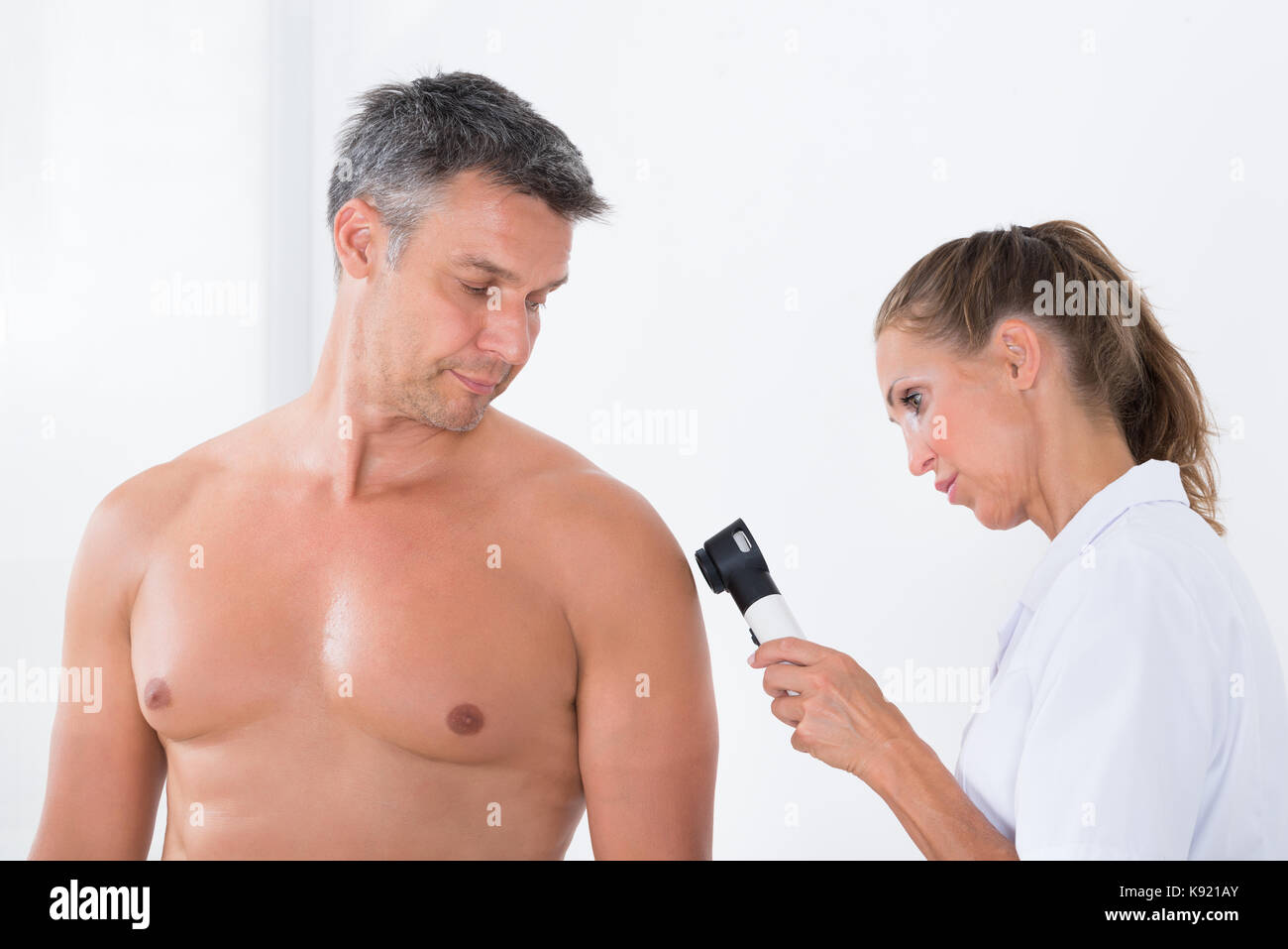 Female Doctor Examining Pigmented Skin Of Patient With Dermatoscope Stock Photo