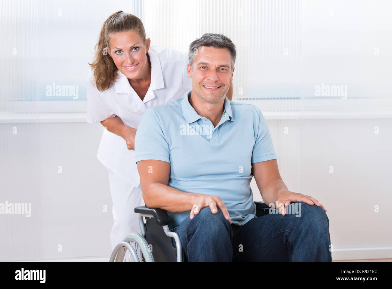 Happy Female Doctor Carrying Male Patient On Wheelchair Stock Photo Alamy