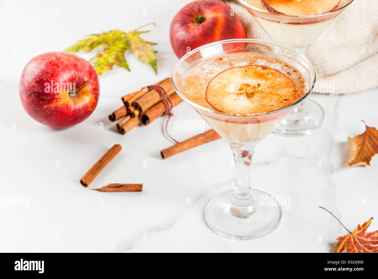 Fall and winter drinks, Apple cider martini margarita with cinnamon and apple garnish, on white marble table, copy space Stock Photo