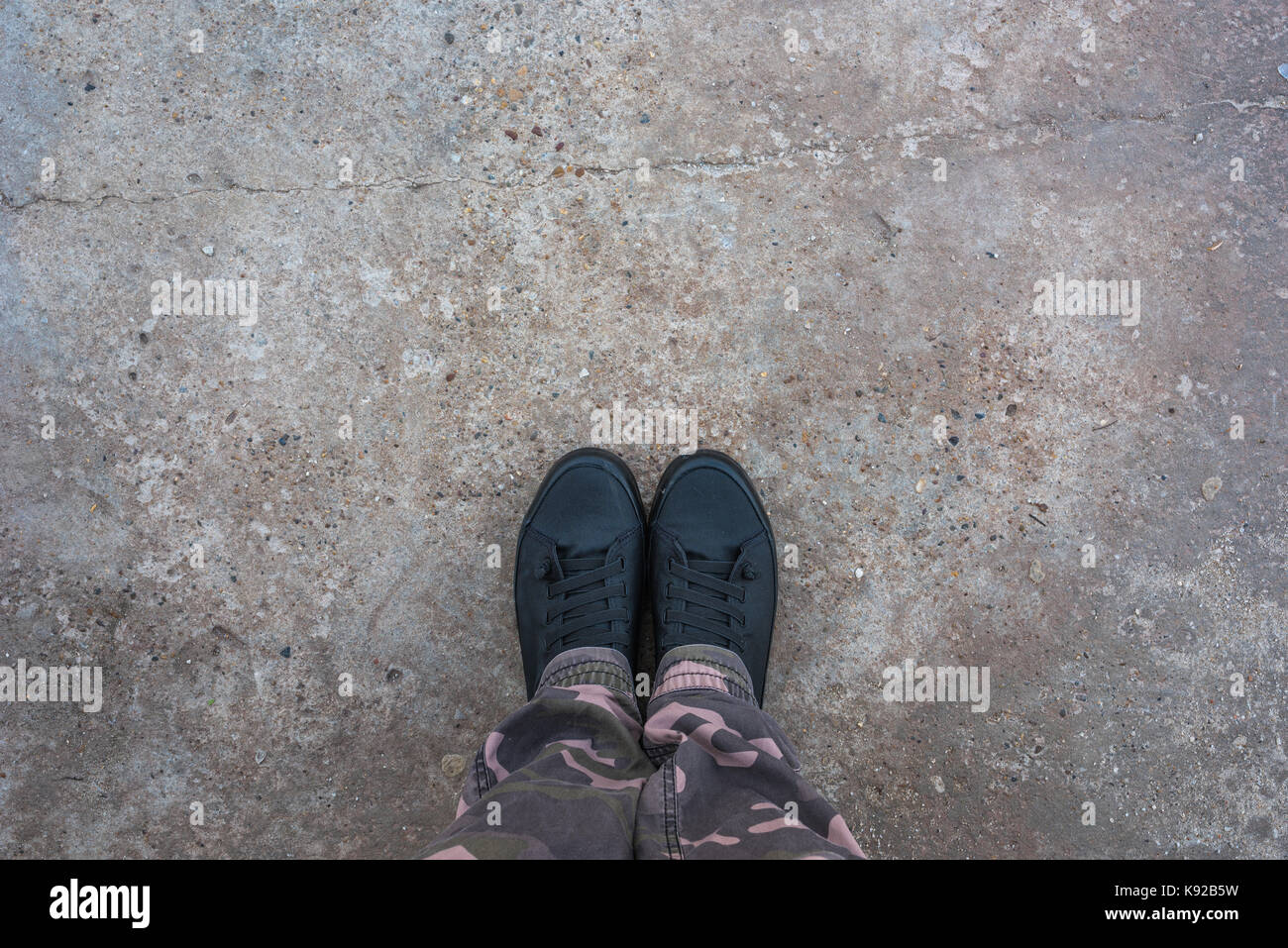 Modern new sneakers on concrete sidewalk surface, young person standing on the street Stock Photo