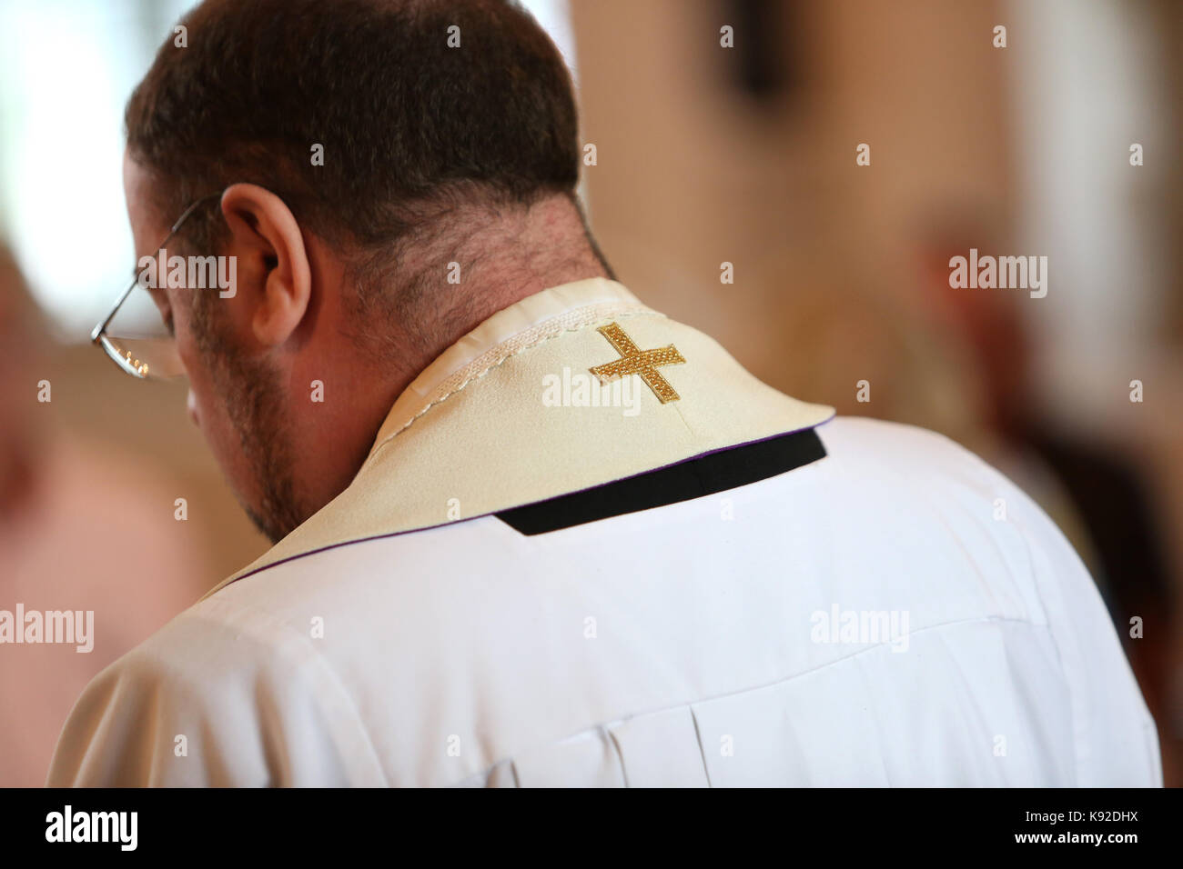 A priest / vicar pictured from behind in a church in Bexhill, East Sussex, UK. Stock Photo
