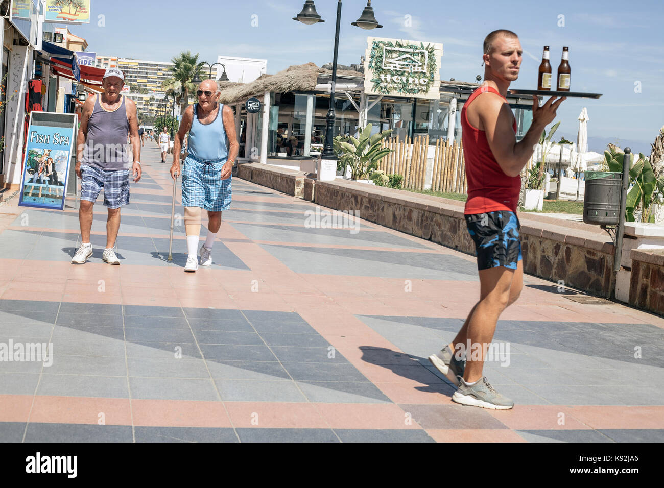 Pensioners walk along the seafront in Torremolinos, Malaga, Spain. Stock Photo