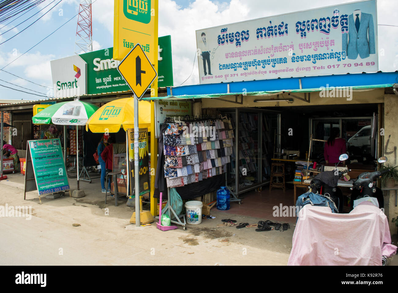 A shop selling textiles and cloth, with samples of different colours and patterns on display outside. In the streets of Phnom Penh, Cambodia, SE Asia Stock Photo
