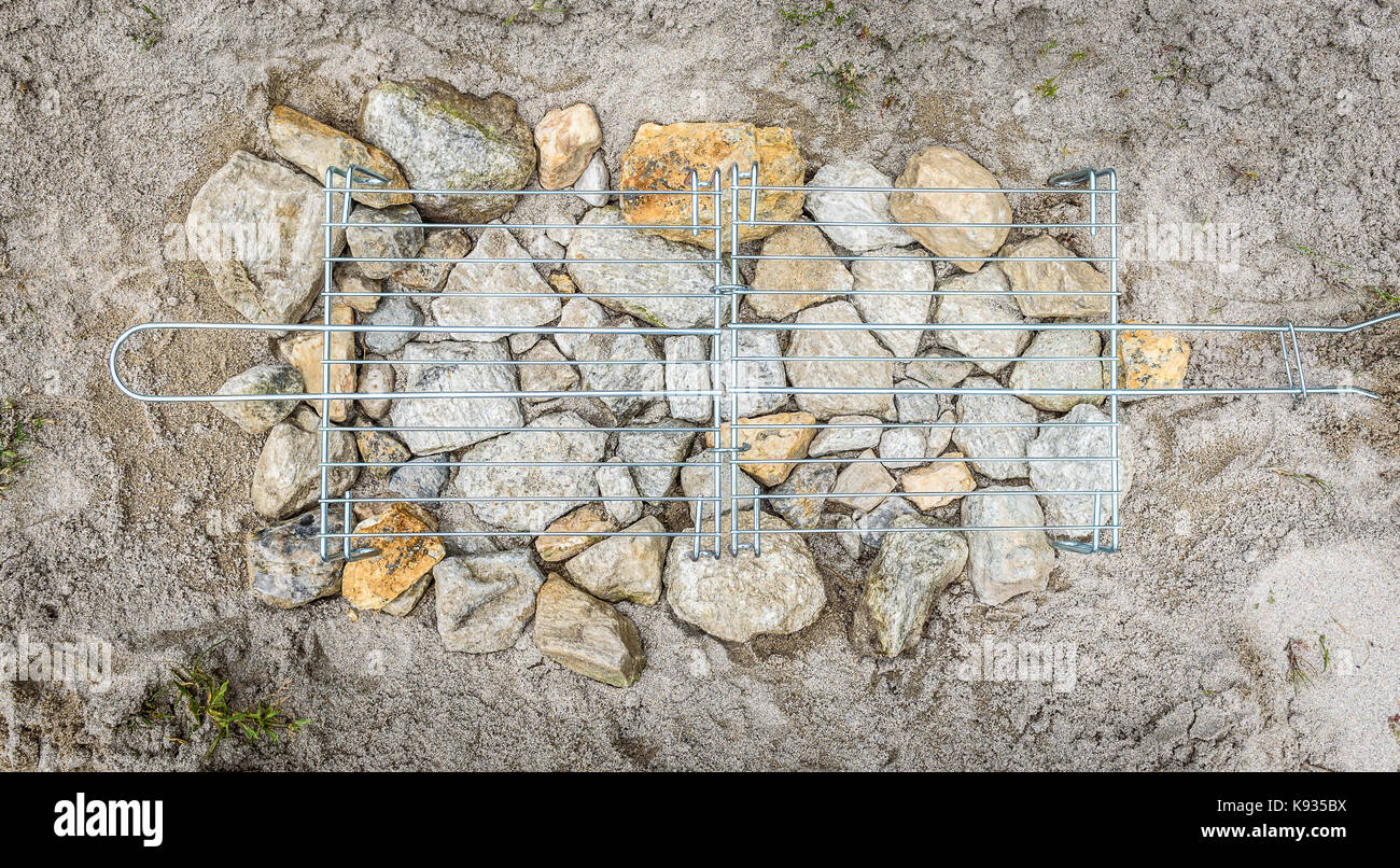 Homemade improvised BBQ barbecue grill on sandy beach on vacation. Making a coal, fire