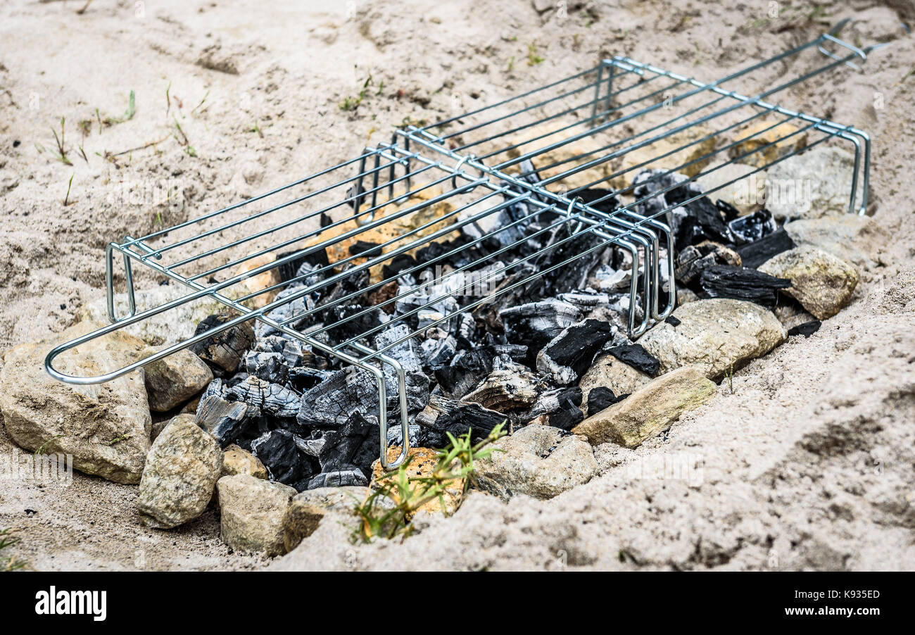 Homemade improvised BBQ barbecue grill on sandy beach on vacation. Making a coal, fire