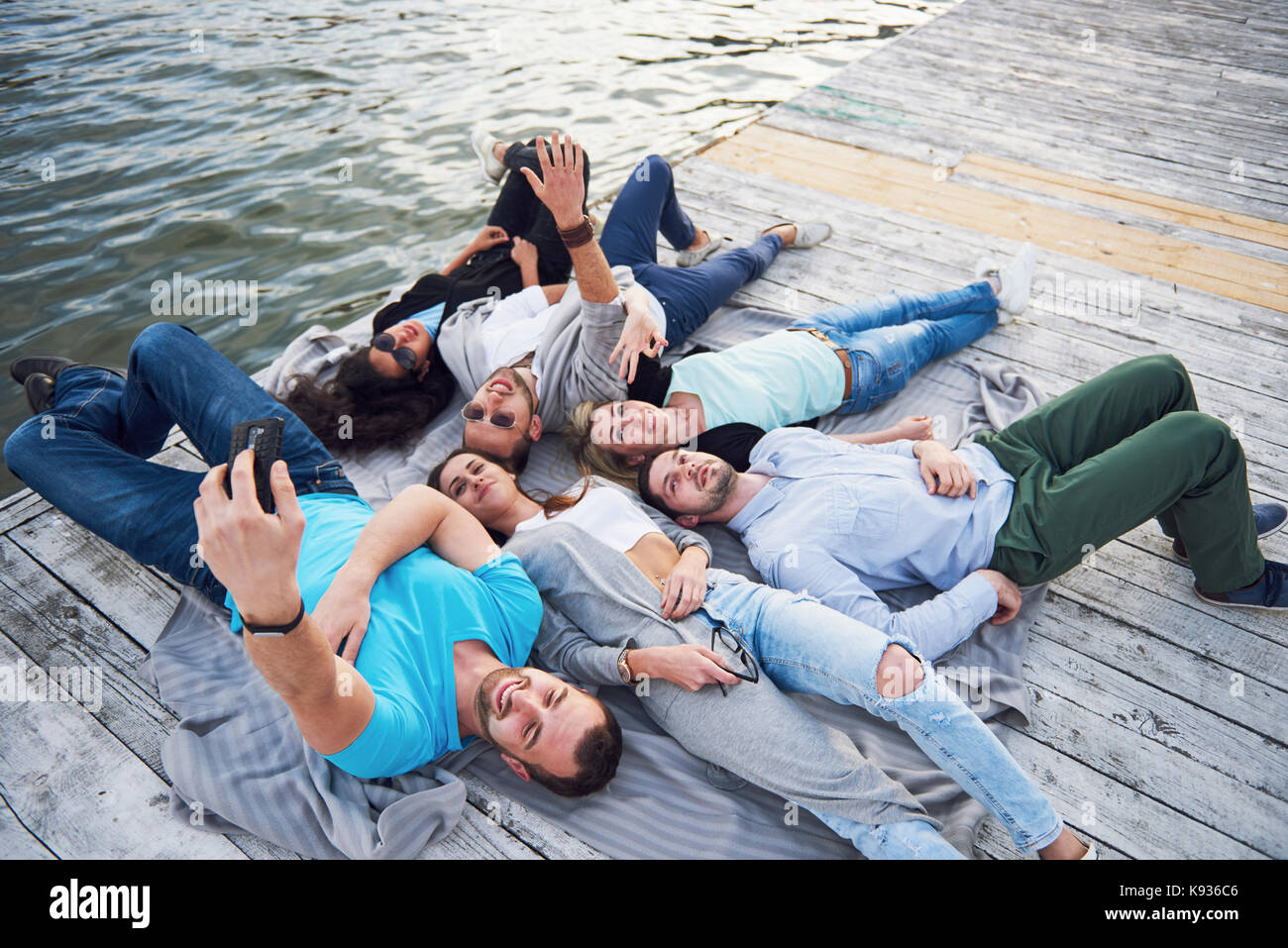 Group of beautiful young people who do Selfies lying on the pier ...