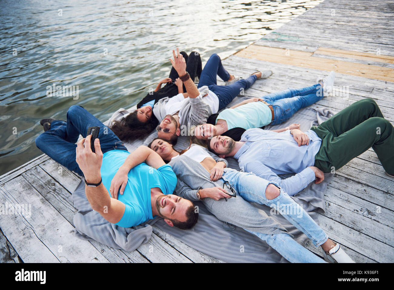 Group of beautiful young people who do Selfies lying on the pier ...