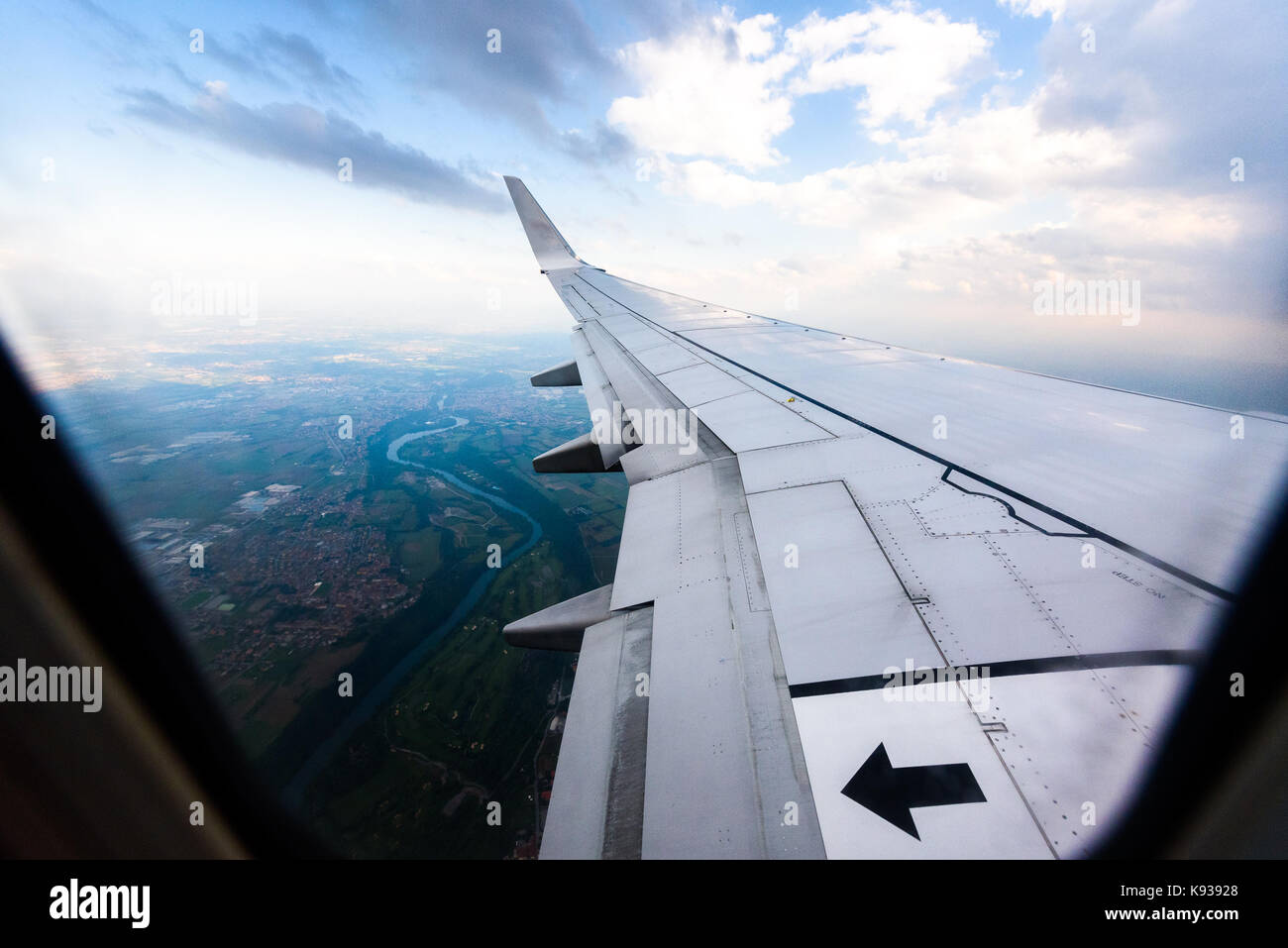 Looking trough window of an aircraft, airplane or plane wing. View from plane window during landing or takeoff over the city urban area. Stock Photo