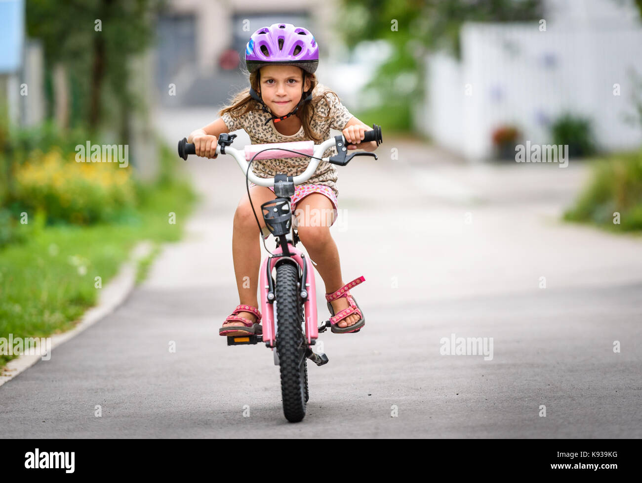 Children learning to drive a bicycle on a driveway outside. Little