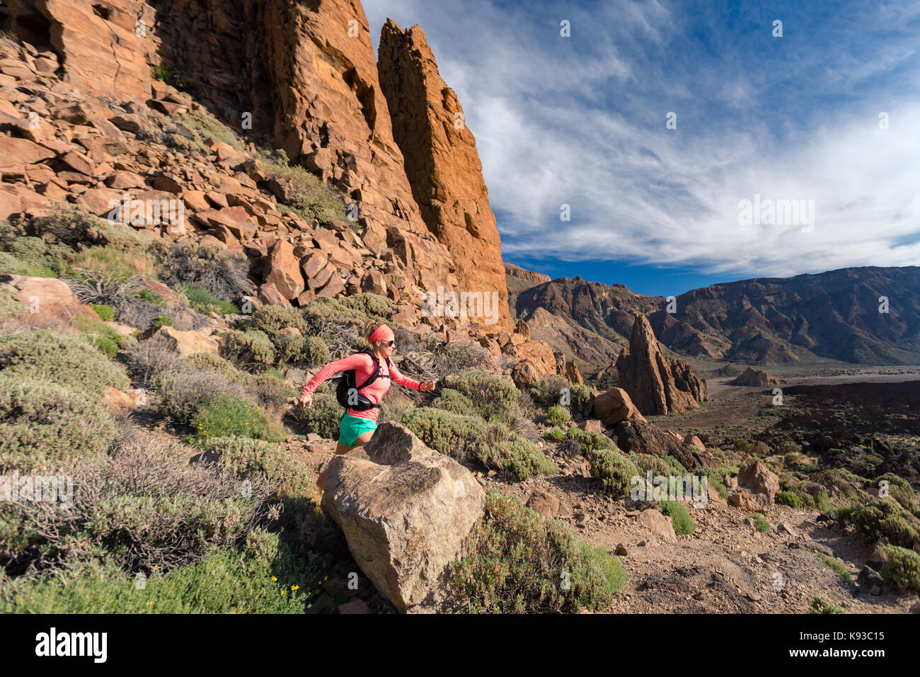 Trail running girl in mountains on rocky path. Cross country runner training with backpack in inspiring nature, dirt footpath on Tenerife, Canary Isla Stock Photo