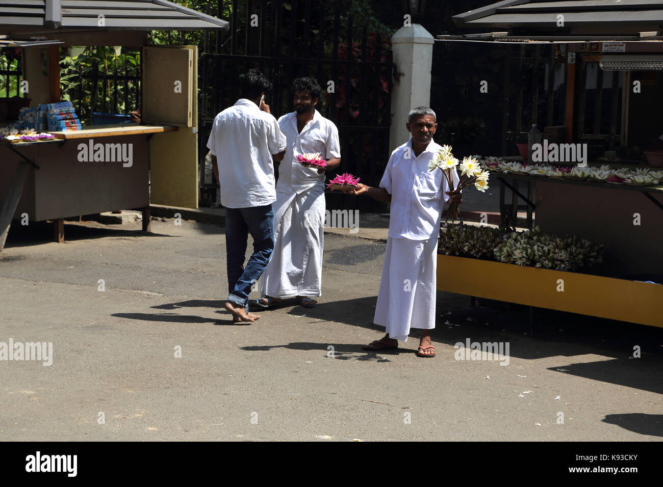 Kandy Sri Lanka Men selling bowls of lotus flowers as offerings outside the Temple of the Sacred Tooth Relic Stock Photo