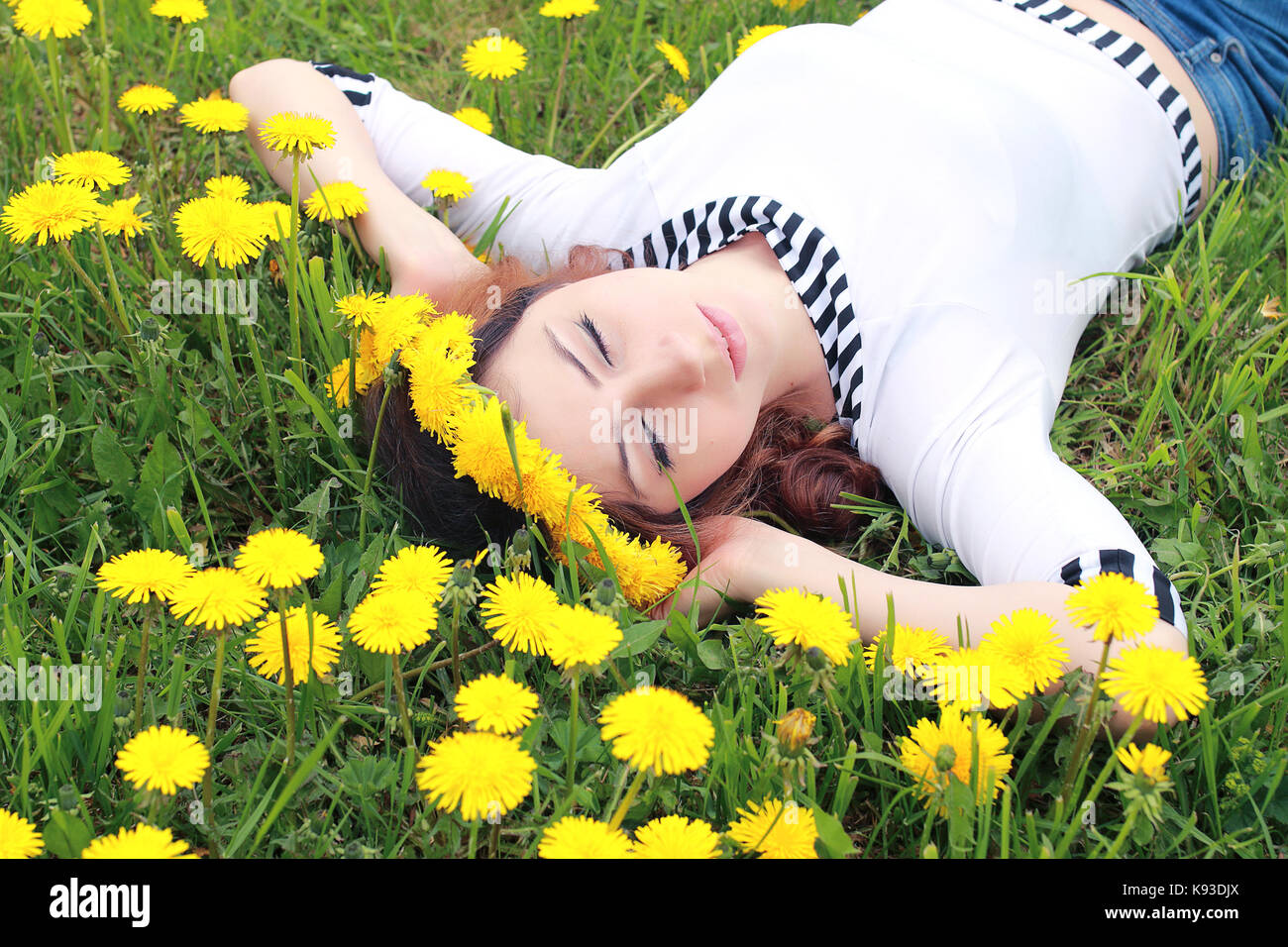 girl resting on a sunny day in meadow of yellow dandelions Stock Photo ...