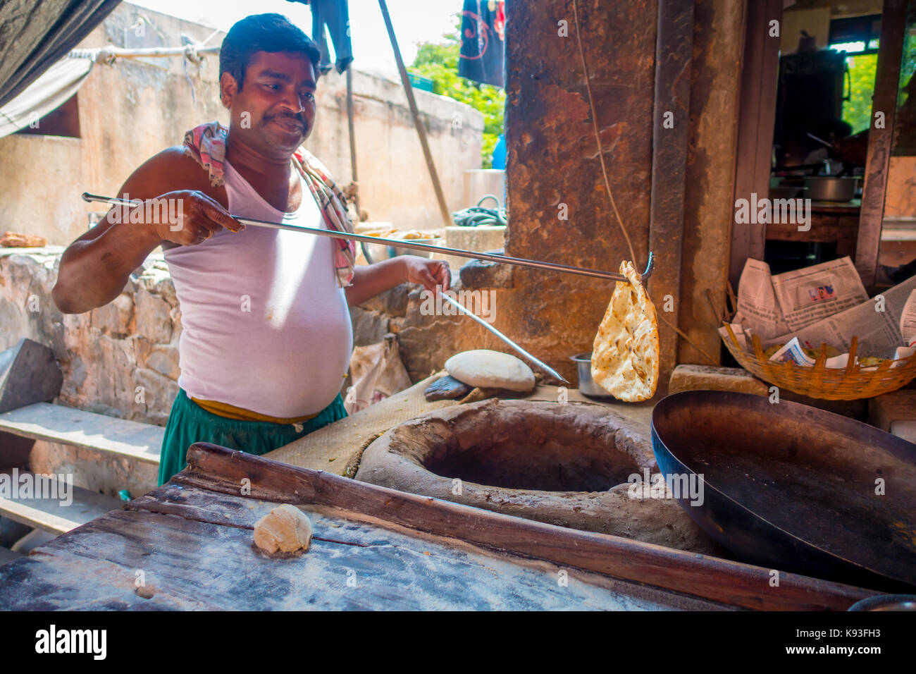 Jaipur, India - September 20, 2017: Unidentified man cooking in the kitchen homemade small tortillas inside of a stone oven, for breakfast in Jaipur city, in India Stock Photo