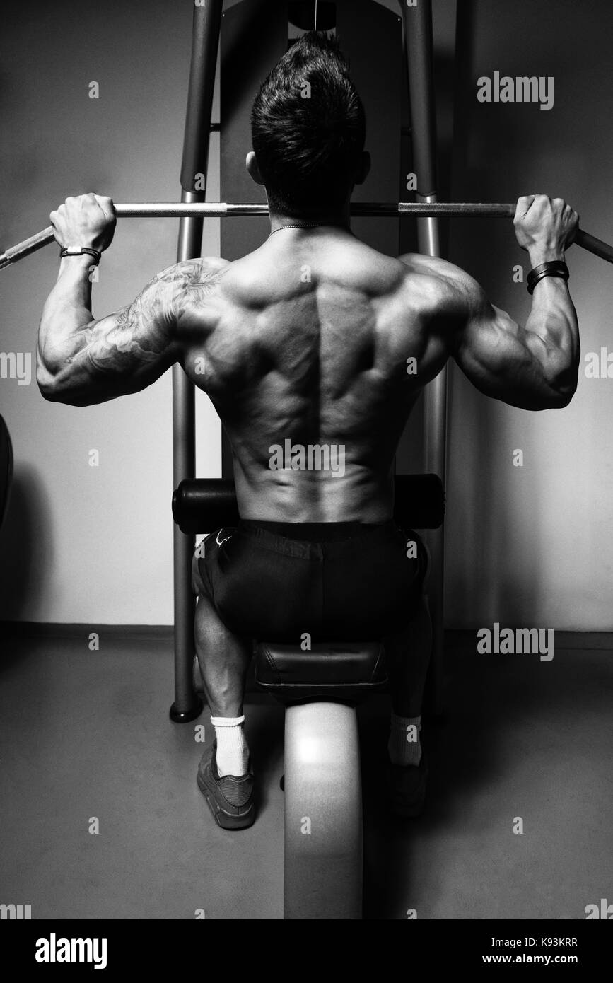 Handsome Athlete Doing Heavy Weight Exercise For Back On Machine Stock