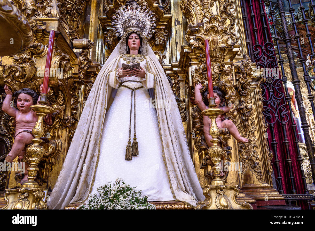 Religious statue of female saint wearing crown, white gown and holding