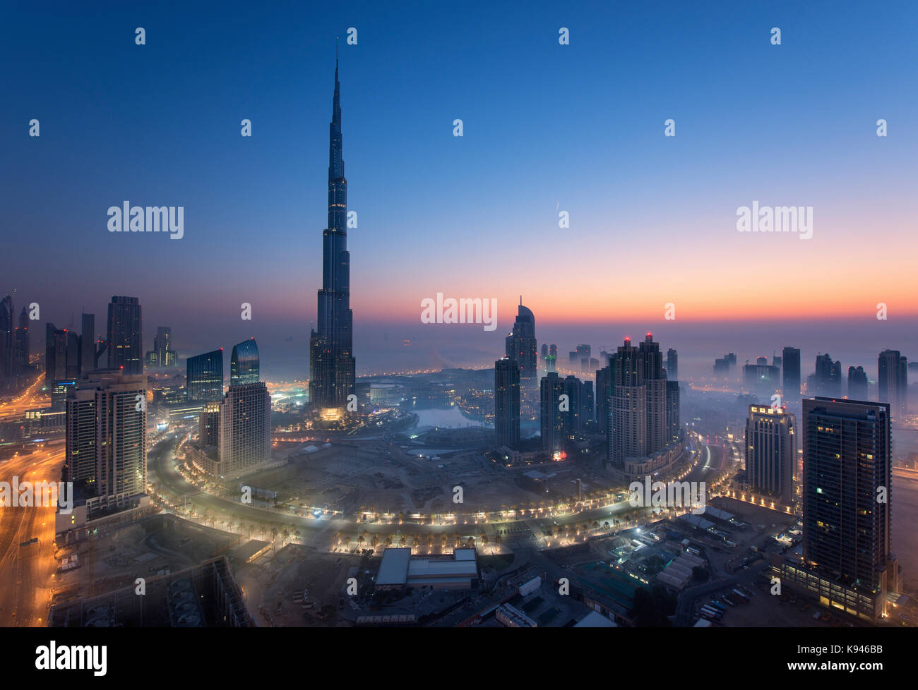 Cityscape of Dubai, United Arab Emirates at dusk, with the Burj Khalifa skyscraper and illuminated buildings in the foreground. Stock Photo
