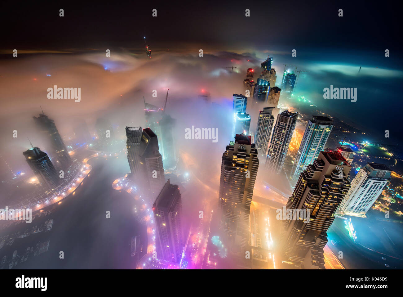 Aerial view of cityscape with illuminated skyscrapers above the clouds