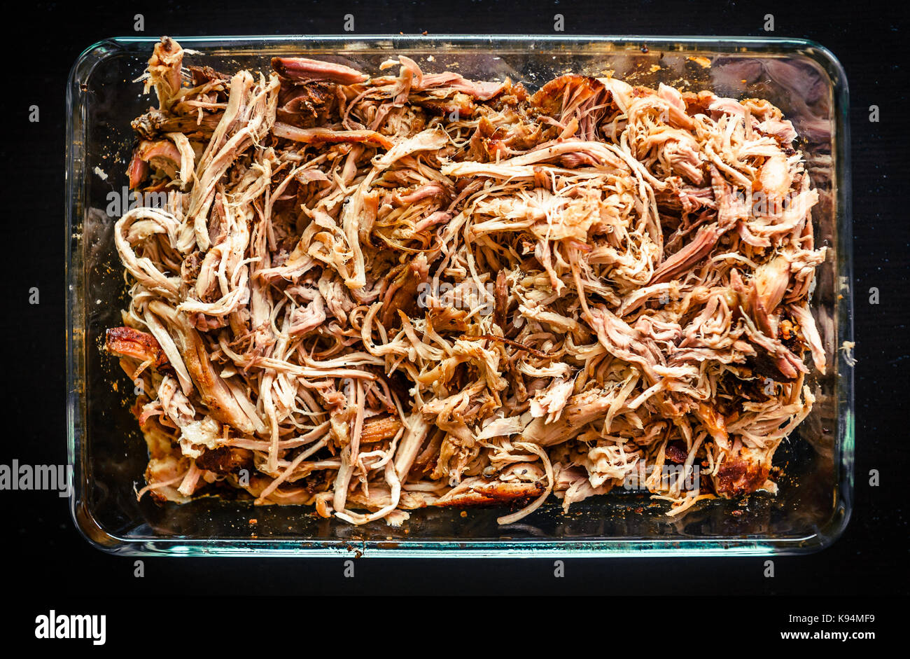 Pulled pork from oven in glass bowl ready for serving. Home made pulled pork made in house oven, smoker or barbecue bbq is ready to be eaten. Stock Photo