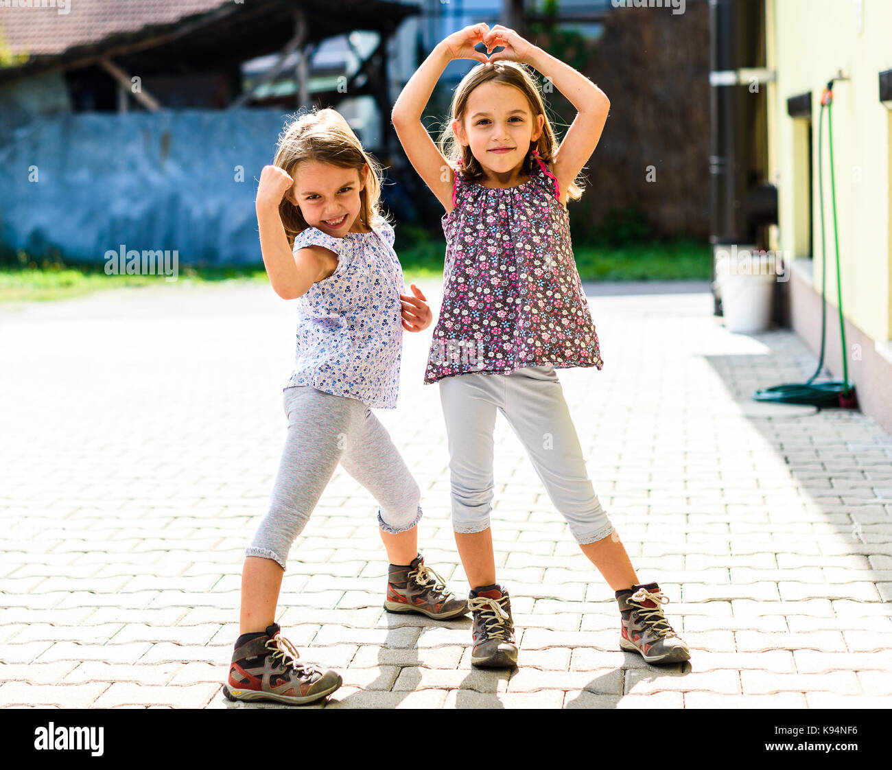 Children - twin girls are going hiking in the mountains. Children, ready for outdoor pursuit are standing in front of their home, ready to go for a hi Stock Photo