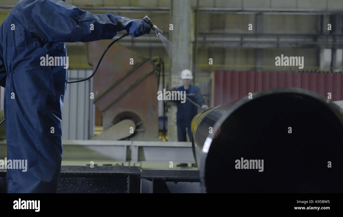 Man paints pipe atomizer. Mens hand paint the pipes on the plant ...