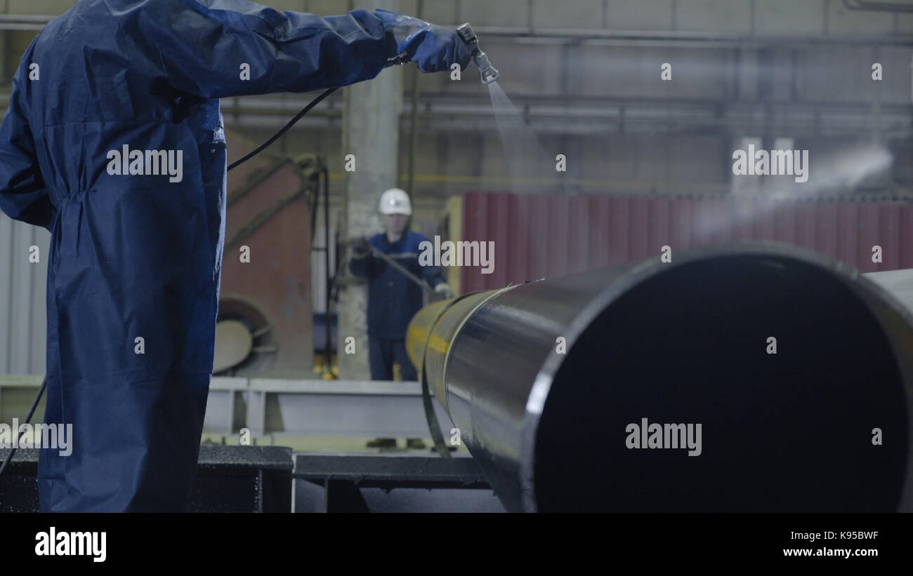 Man paints pipe atomizer. Mens hand paint the pipes on the plant ...
