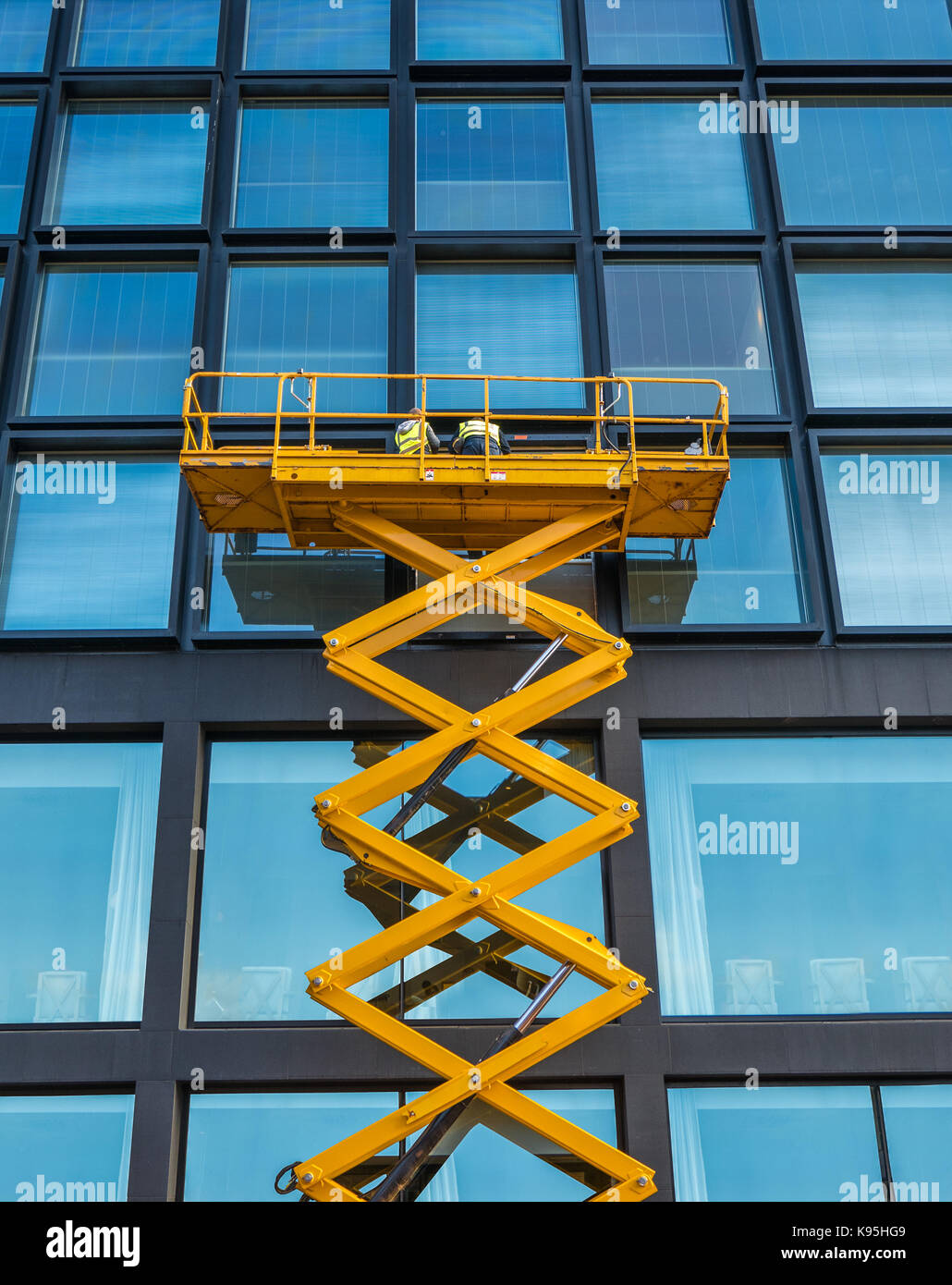 Workers On A Scissor Lift Cleaning Windows On A Financial Building