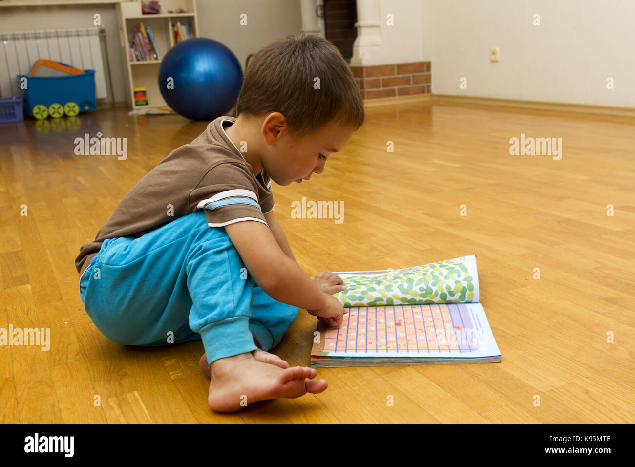 Little boy is sitting on the floor with a book Stock Photo - Alamy