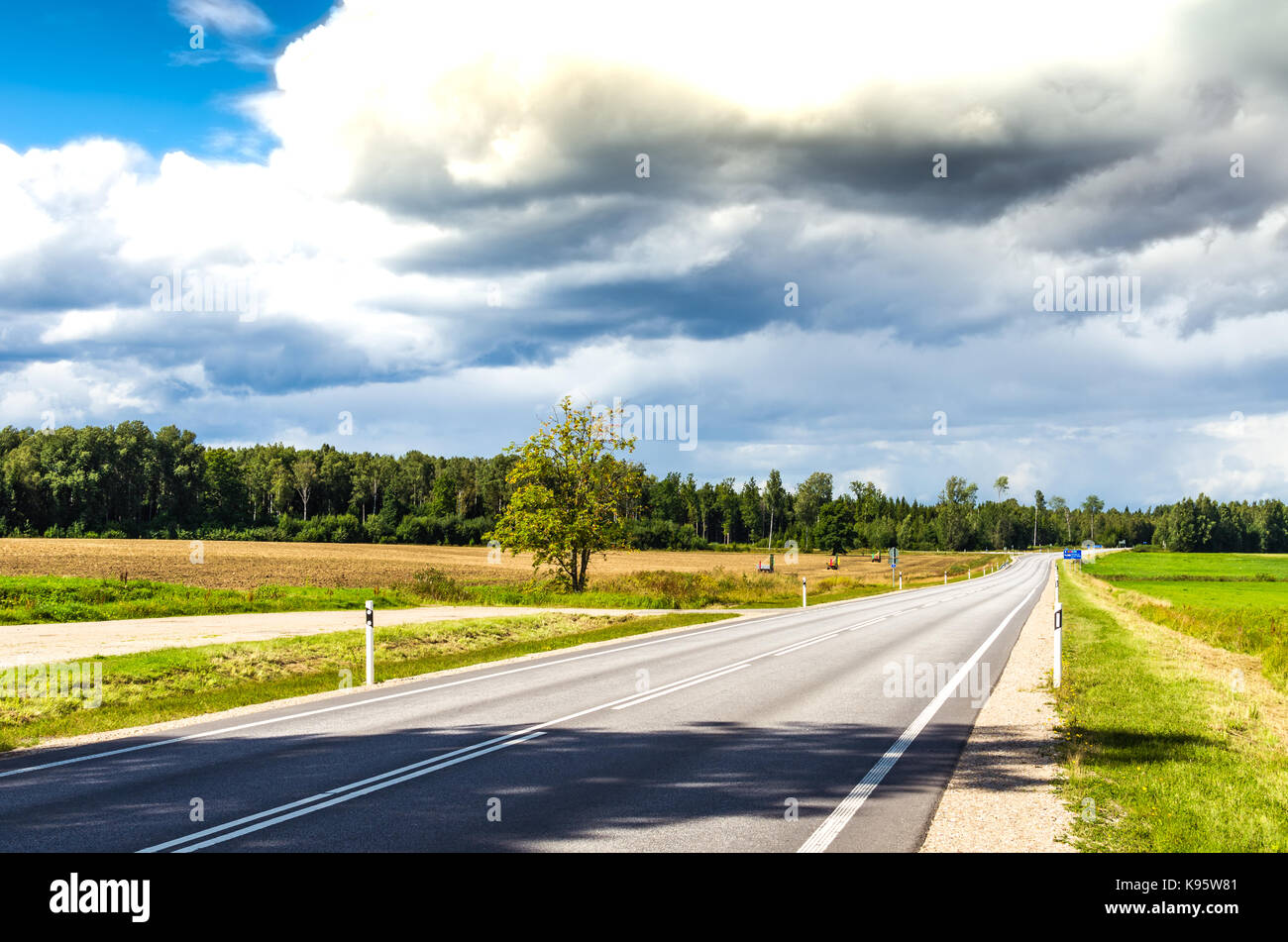 A road in the countryside under a cloudy sky Stock Photo
