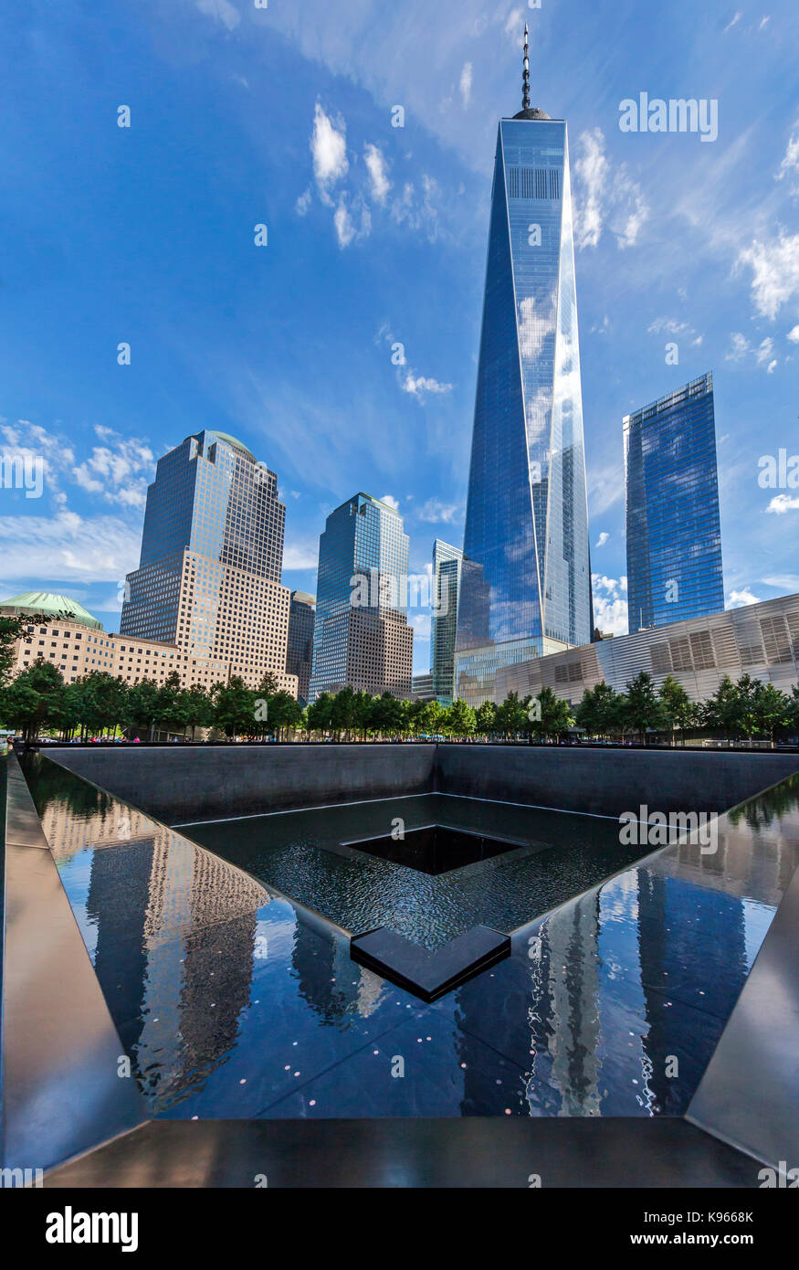 Tourists and visitors visit the  September 11 Memorial South Pool with the Freedom Tower visible in the background. Stock Photo