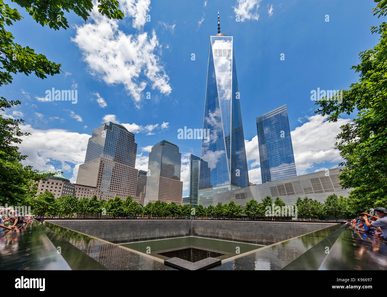 Tourists and visitors visit the  September 11 Memorial South Pool with the Freedom Tower visible in the background. Stock Photo