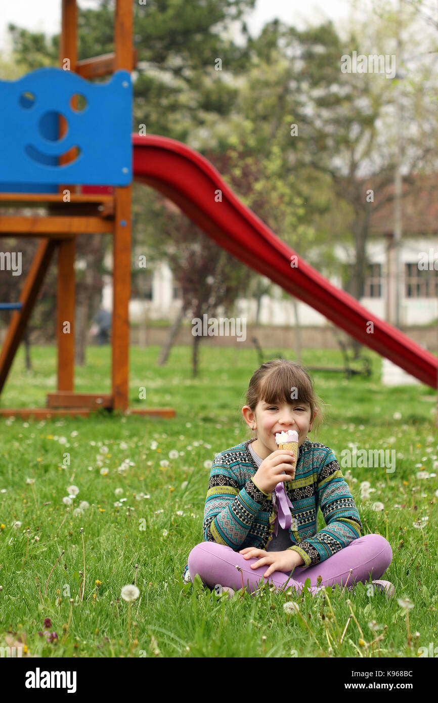 happy little girl sitting on grass and eat ice cream Stock Photo - Alamy