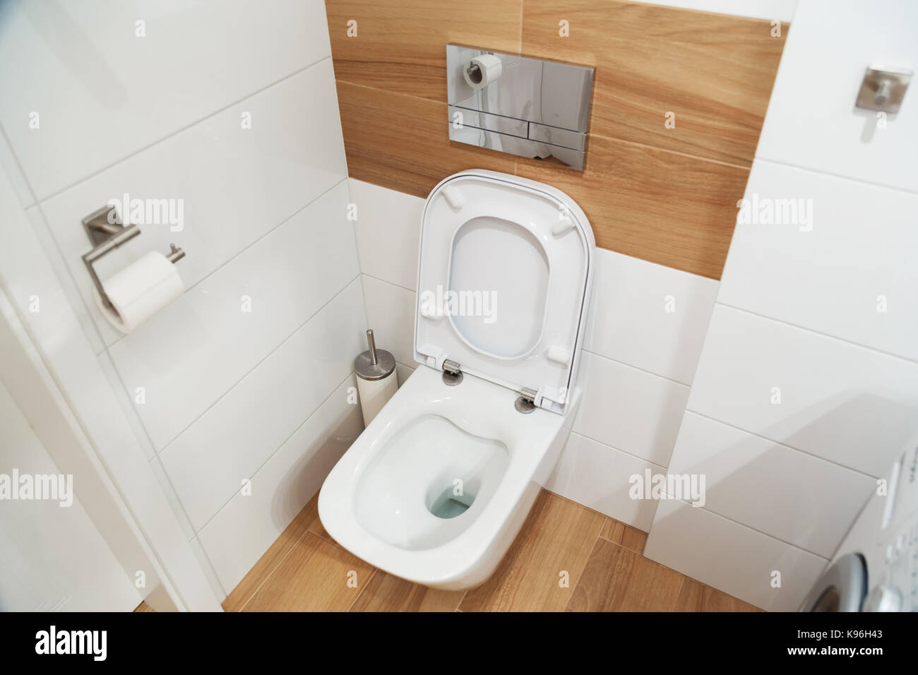 Modern hinged toilet bowl with a tank built into the wall. Opened lid