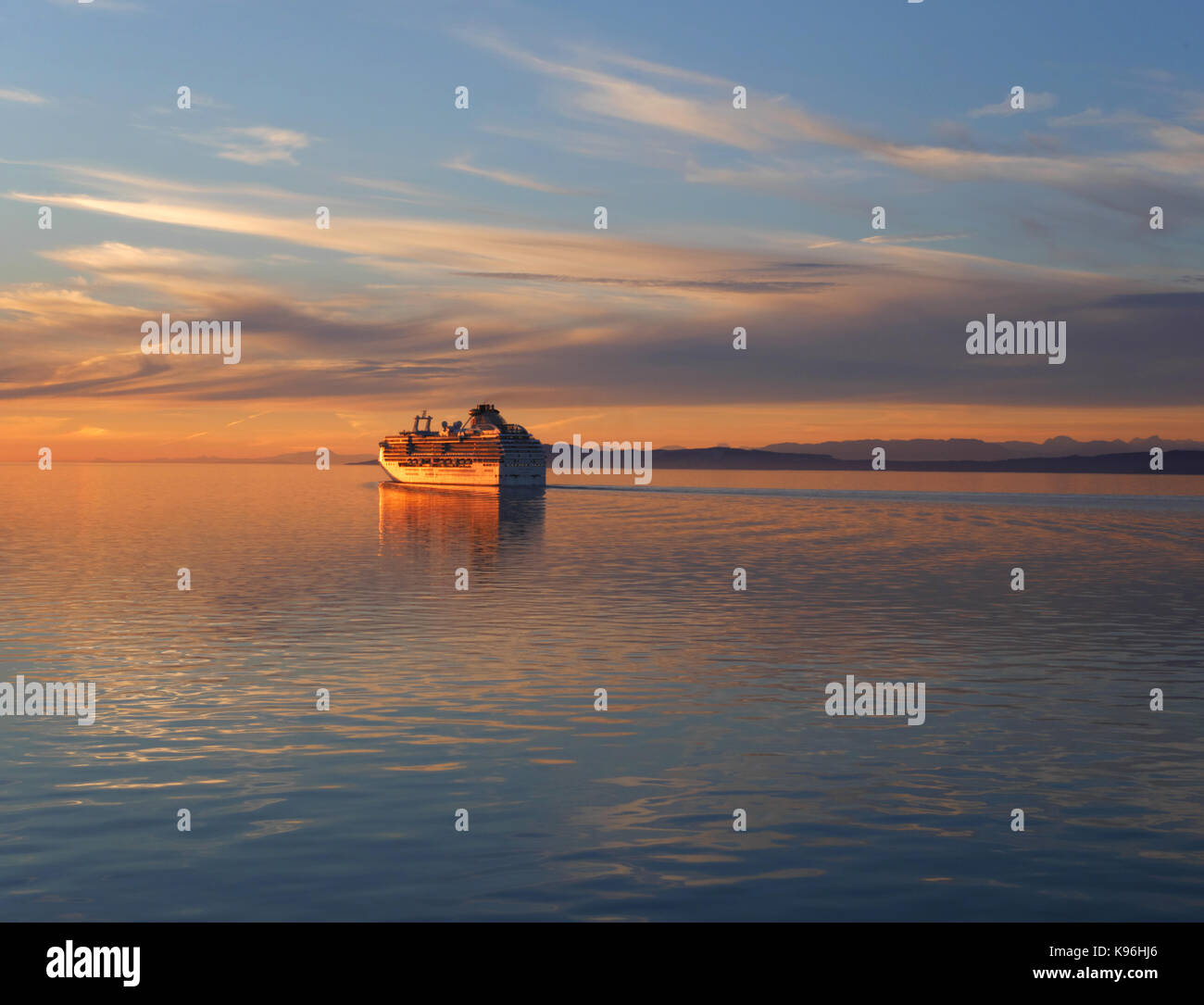 The sun sets behind the cruise liner 'Coral Princess' as she sails into the Straits of Georgis from Vancouver, BC, Canada. Stock Photo